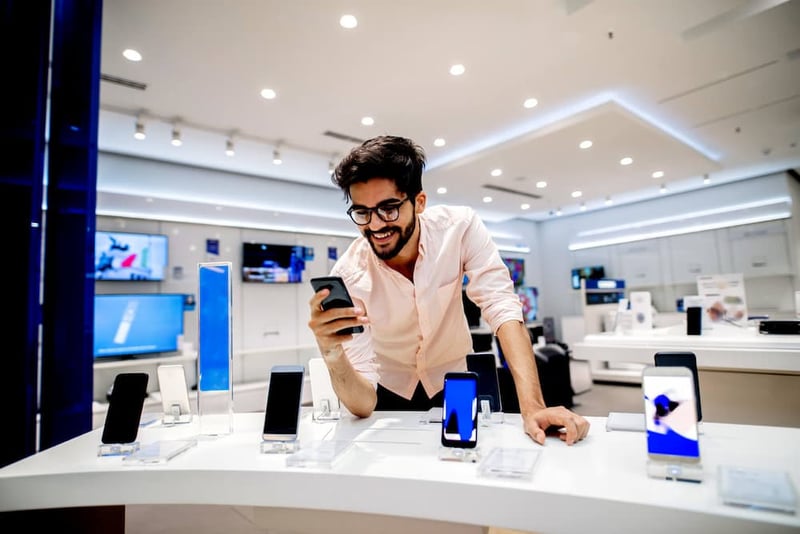 customer in wireless retailer looking at a smartphone smiling after finding a great deal